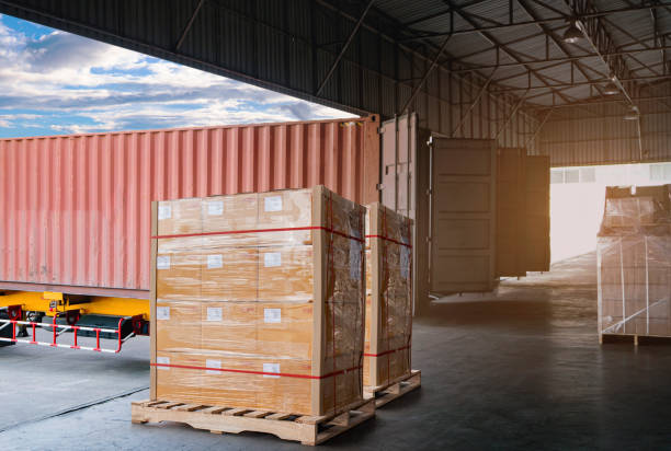 istock Cargo shipment loading for truck. Freight truck for delivery service. Logistics and transportation. Warehouse dock load pallet goods into container truck. Stacked boxes wrapped plastic on pallet rack. 1300769820