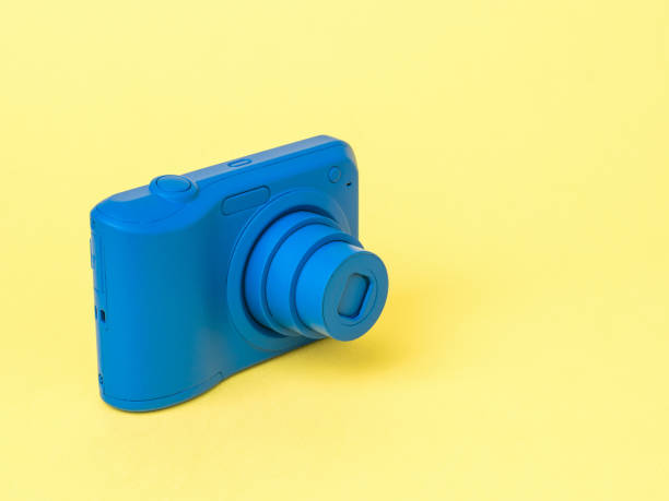 istock Stylish blue camera with extended lens on a yellow background. 1300770534
