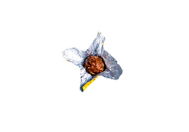 Round chocolate candies in a foil wrapper on a white background. Sweet cake. Silver wrapper. Shiny foil. Candy wrapper. Sweet dessert. White background. Background image.
