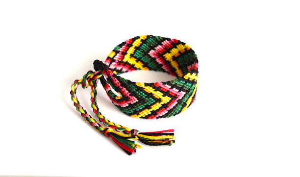 istock Tied woven friendship bracelet with bright colorful pattern handmade of thread on white background 1300773335