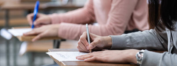 istock Close up of a woman student writing on notepad placed on wooden desktop 1300776884