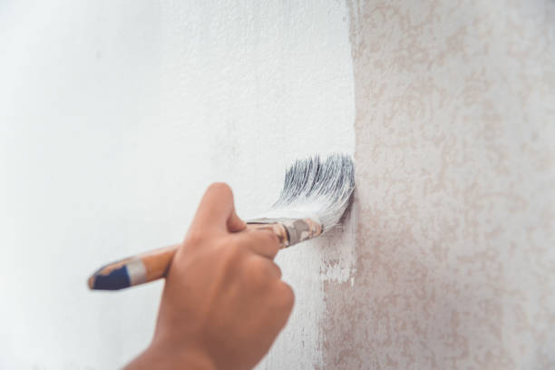 istock hand was holding a brush to paint the wall using white paint. 1300776961