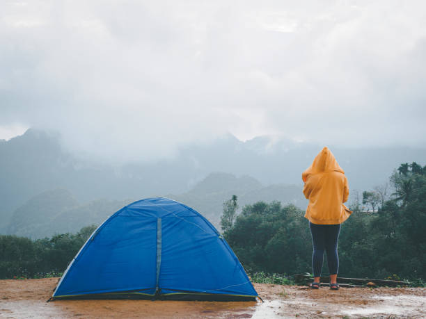 mulher acampando tenda azul no pico da montanha e desfrutando de bela natureza de colinas e durante a estação chuvosa em doi tapang, distrito de sawi, chumphon, tailândia. - chumphon - fotografias e filmes do acervo