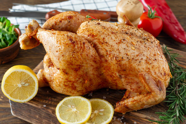 istock Whole roasted chicken with lemon and vegetbles on cutting board. Wooden rustic background 1300782907