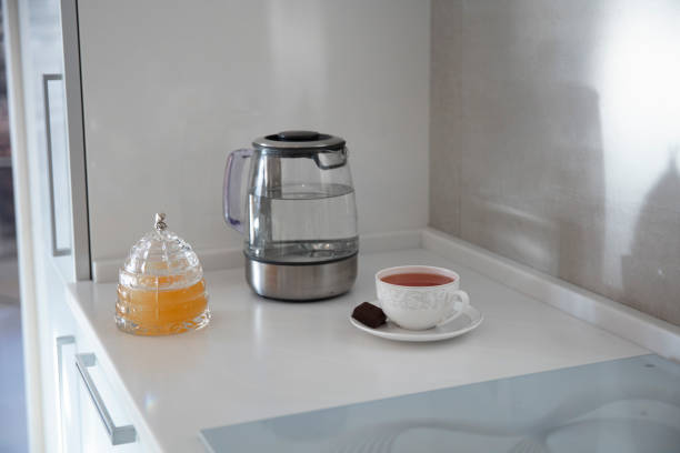 istock Kitchen table top, a cup of tea, kettle, honey, dessert on the table top. Mockup, template. Empty space for household appliances. 1300783077