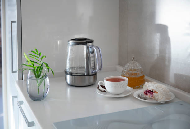 istock Kitchen table top, a cup of tea, kettle, honey, dessert on the table top. Mockup, template. Empty space for household appliances. 1300783875