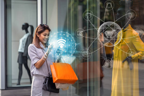 Asian woman using the smart mobile phone for check online shopping order is completed via omni channel technology with clothes beside the glassess in store shop with happy action at department center stock photo