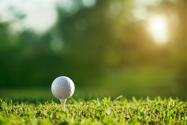 golfball auf abschlag in einem schönen golfplatz mit morgensonne - golf golf flag sunset flag stock-fotos und bilder
