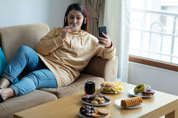 young woman eating junk food at home - food staple audio imagens e fotografias de stock