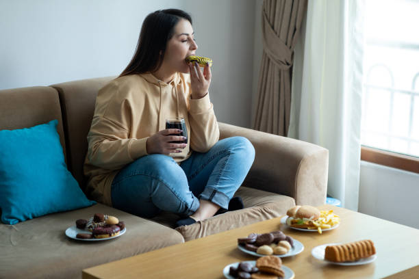 manger des aliments sucrés sur le canapé - high calorie photos et images de collection