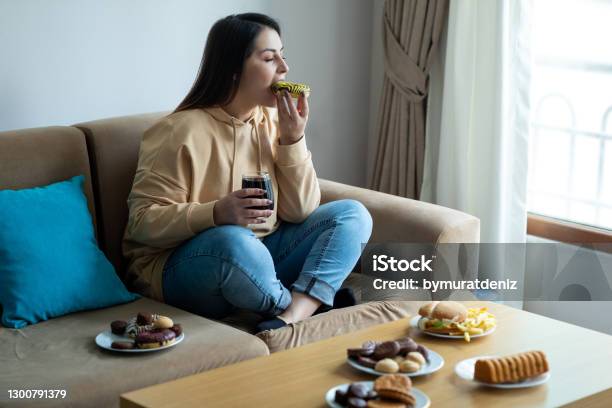 Eating Sugary Food On Sofa Stock Photo - Download Image Now - Eating, Sugar - Food, Food