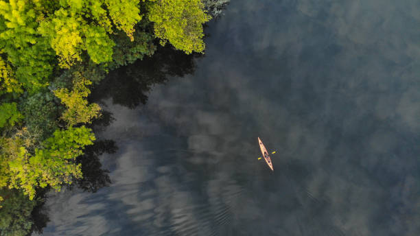 vista aerea superiore del fiume lungo il quale galleggia un piccolo kayak arancione. alberi verdi crescono sulla riva. ecosistema. ucraina - kayaking kayak river sport foto e immagini stock