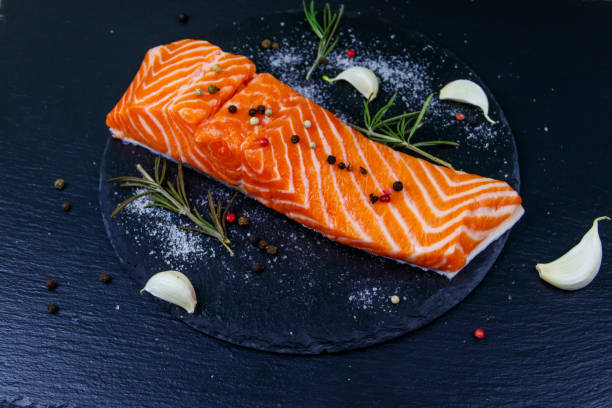 istock Raw salmon fillet with spices on black slate 1300793631