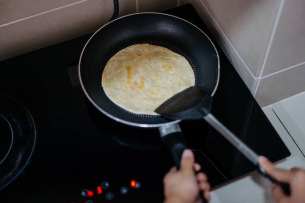 istock Woman heating a paratha with an electric stove in kitchen 1300794555