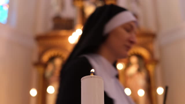 Nun in a Catholic church lights a candle.
