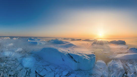 large glaciers in the bay by the rocky shore in the light of the setting sun