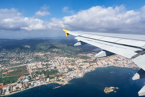 beautiful view from a plane, of the island and the sky of Ibiza, Balearic Islands, Spain. White airplane wing in flight