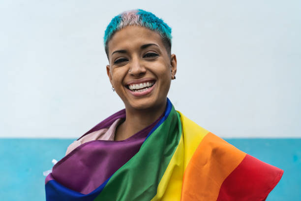 junge aktivistin frau lächelnd und halten regenbogen-flagge symbol der lgbtq soziale bewegung - homosexual gay man parade flag stock-fotos und bilder