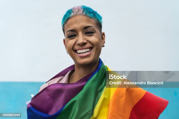 Young Activist Woman Smiling And Holding Rainbow Flag Symbol Of Lgbtq Social Movement Stock Photo - Download Image Now