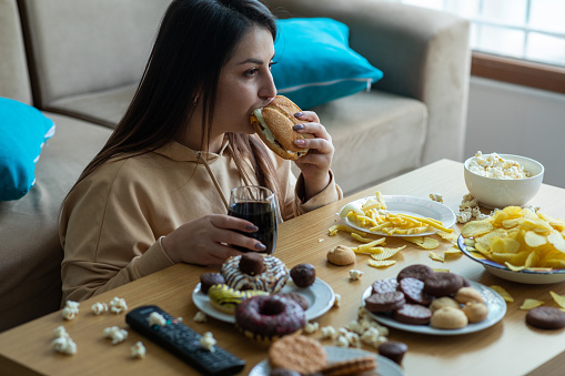 Mujer joven con sobrepeso comiendo comida chatarra photo
