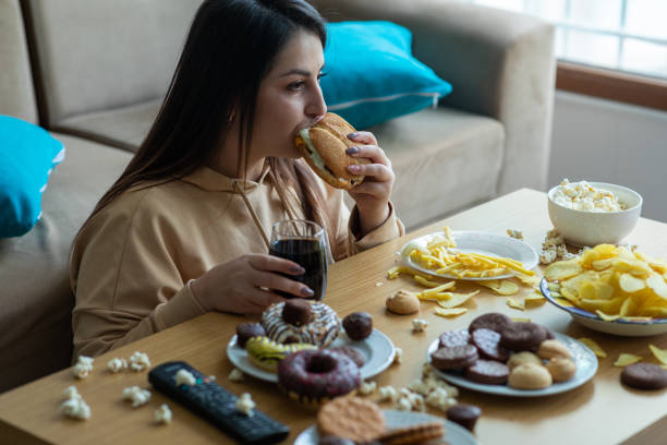 overweight young woman eating junk food - remote fat overweight dieting imagens e fotografias de stock