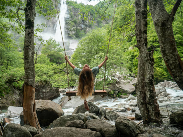 istock Woman on swing near waterfall, green lush forest 1300804071