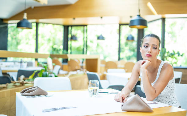 istock Sad woman sitting in empty restaurant 1300804256