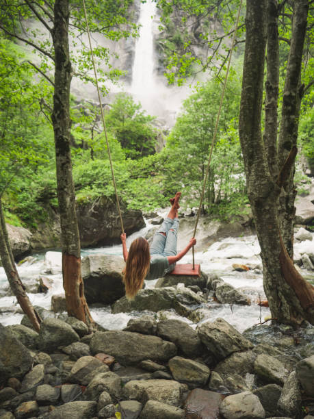 istock Woman on swing near waterfall, green lush forest 1300804811