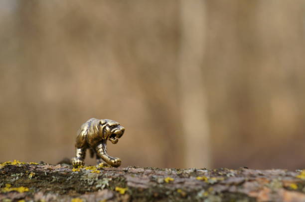 A small, red, wooden, carved statue of a Chinese tiger (one of the Chinese Zodiak animals).  The figurine sits on sandstone rocks, with sandstone hills, desert plants and a blue sky in the background.  The image is said to bring good luck.