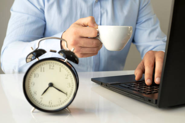 istock Close up alarm clock with young Businessman using laptop analysis marketing plan and drinking coffee in the morning. Business, Finance and lifestyle concepts 1300808458