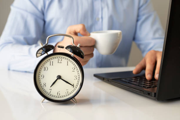 istock Close up alarm clock with young Businessman using laptop analysis marketing plan and drinking coffee in the morning. Business, Finance and lifestyle concepts 1300808459