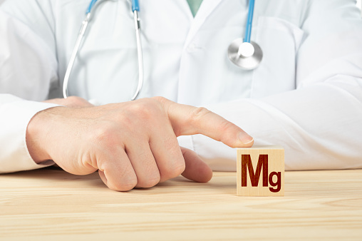 essential element and minerals for humans. doctor recommends taking magnesium. doctor talks about the benefits of magnesium. magnesium- Health Concept. Mg alphabet on wood cube.