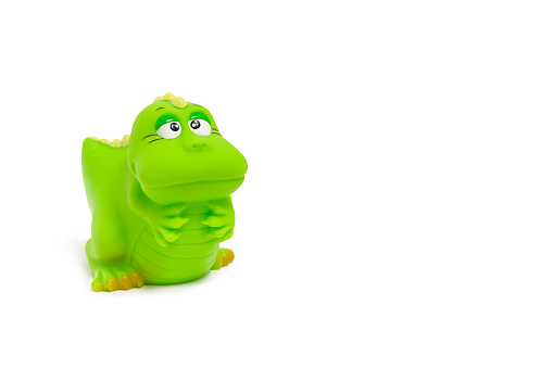 green cute dinosaur - rubber bathing toy close up isolated on white, copy space to the right