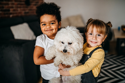 Kids playing with dog in living room, embracing him