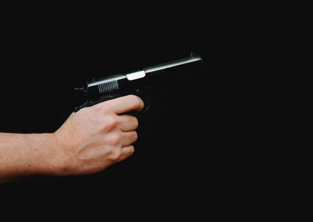 istock Hand holding a gun, isolated on black background. 1300813010