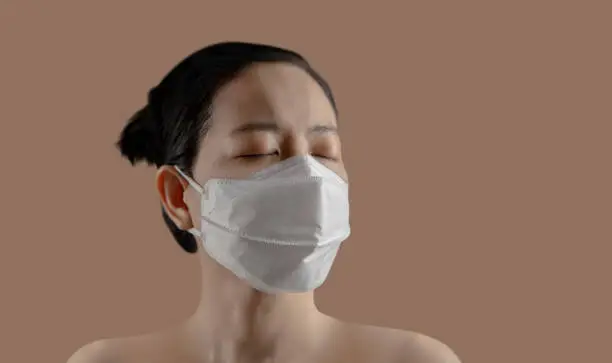 Positive Mindful during Coronavirus or Air Pollution Situation. Mental Health Concept. Head shot of Asian Woman wearing a Surgical Mask. Eyes Closed and Stay Calm