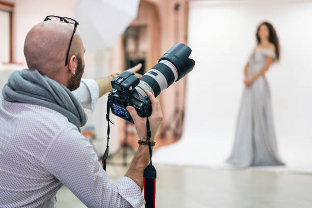 fotógrafo de moda filmando una sesión de fotos con una modelo en un estudio - operador de cámara fotos fotografías e imágenes de stock