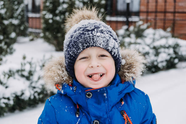 nahaufnahme outdoor-winterporträt von jungen gesicht im schnee. authentische, echte, ehrliche porträt von niedlichen jungen im winter. kleines kind in winterkleidung, das unter dem schnee spazieren geht - little boys sled clothing slide stock-fotos und bilder