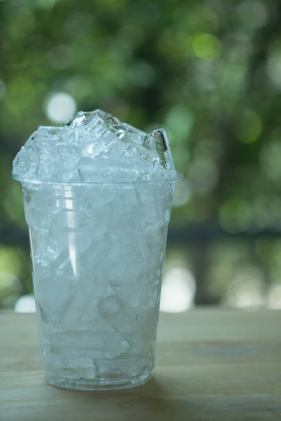 Ice in plastic glass on wood table. Close up