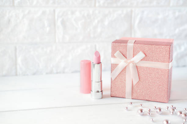 istock pink lipstick and a gift box on a table. pink necklace. 1300818167