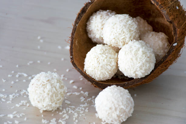 Coconut candy dessert Homemade sweets white coconut candy balls in nut shell on wooden background. Recipe of delicious white chocolate truffles in coconut flakes. chocolate white chocolate chocolate chip white stock pictures, royalty-free photos & images