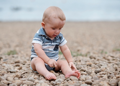 Small boy playing with stones on the seaside
