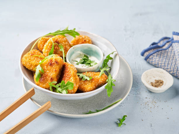 nuggets vegetarianos com molho de mergulho vegano e folhas de foguete em um fundo leve com espaço de cópia, foco seletivo. dieta saudável, conceito de refeições vegetarianas proteicas, produtos de carne alternativa. - fried tofu tofu vegetable vegetarian food - fotografias e filmes do acervo