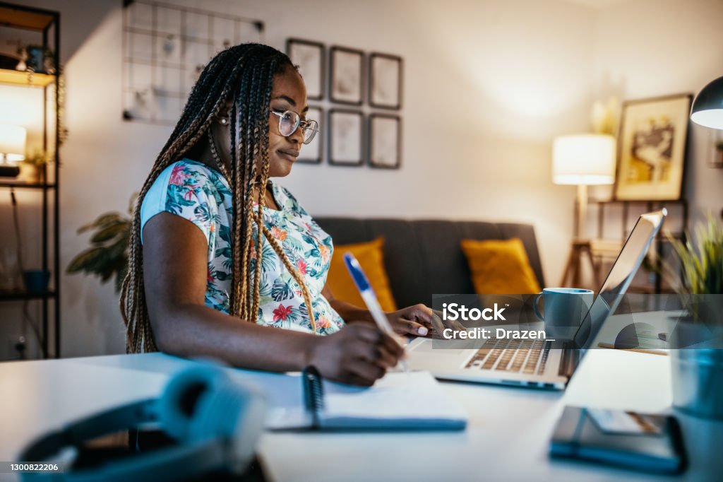 African American female student studying from home and taking notes from professor African American female student studying from home during lockdown E-Learning Stock Photo