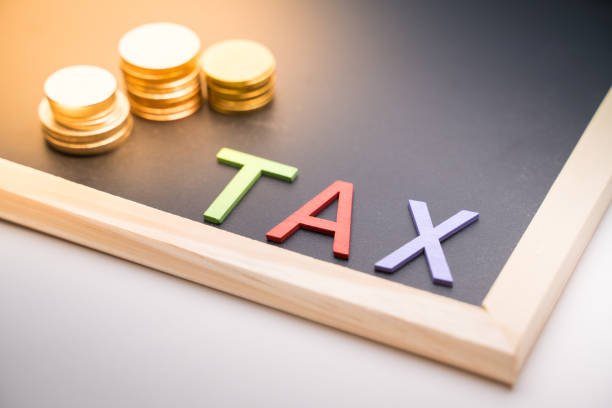 istock Tax text on blackboard with coin under light 1300823650