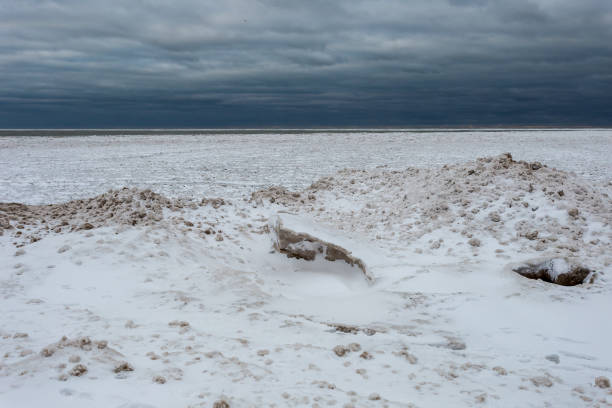 formas de aspecto extraño creadas por la nieve, el hielo y la arena bloquean la entrada de agua en el lago michigan en el sombrío día nublado en chicago - bizarre landscape sand blowing fotografías e imágenes de stock