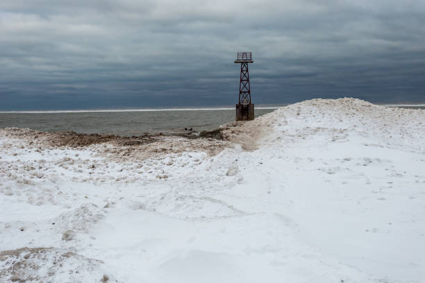 torre de luz marítima rodeada de nieve y hielo masivos en el lago michigan en el sombrío día nublado en chicago - bizarre landscape sand blowing fotografías e imágenes de stock