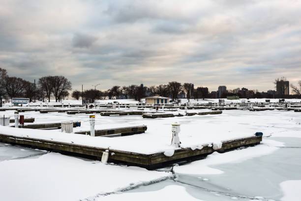 istock Several snow covered docks sitting in an empty marina with frozen ice sheets on cold winter day with overcast sky in urban Chicago 1300823948