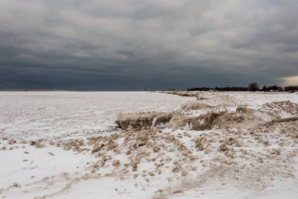 pequeñas bolas de hielo y arena llenas en la parte superior de grandes bloques de nieve y hielo en el lago michigan en el sombrío día nublado en chicago - bizarre landscape sand blowing fotografías e imágenes de stock