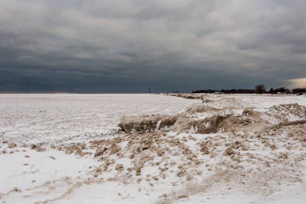 シカゴの暗い曇りの日にミシガン湖の雪と氷の大きなブロックの上に散らばった氷と砂の小さなボール - bizarre landscape sand blowing ストックフォトと画像